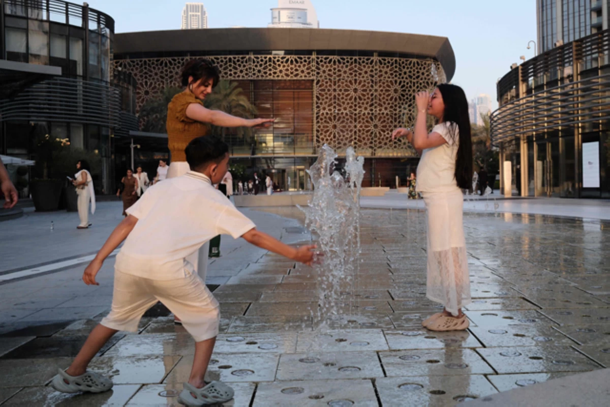 A woman and children cool off in a fountain in front of Dubai Opera on Saturday, as summer temperatures sore in the Emirati city (AFP photo)