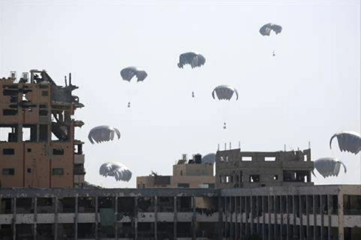 Aid packages parachute down near Jabalia in the northern Gaza Strip on August 14, 2025. (AFP)