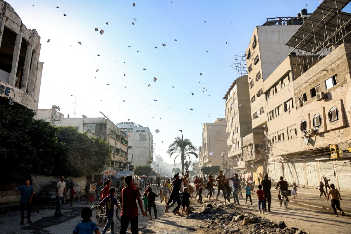 People watch as leaflets dropped by the Israeli military, urging evacuation south to al-Mawasi, land in Gaza City on September 9, 2025. (AFP photo)