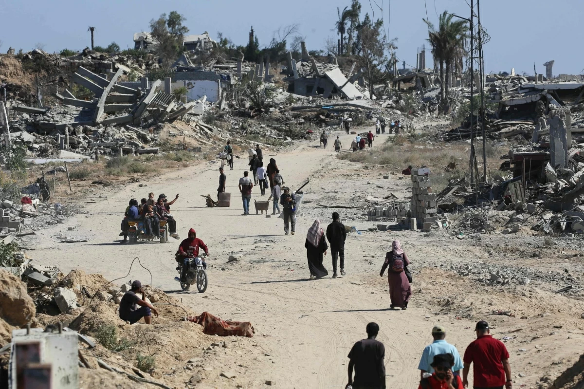 Displaced Palestinians walk past destroyed buildings as they return to their homes in the in al-Zahra area, north of the Nuseirat refugee camp in the central Gaza Strip, on October 14, 2025, a day after a ceasefire came into effect (AFP photo)