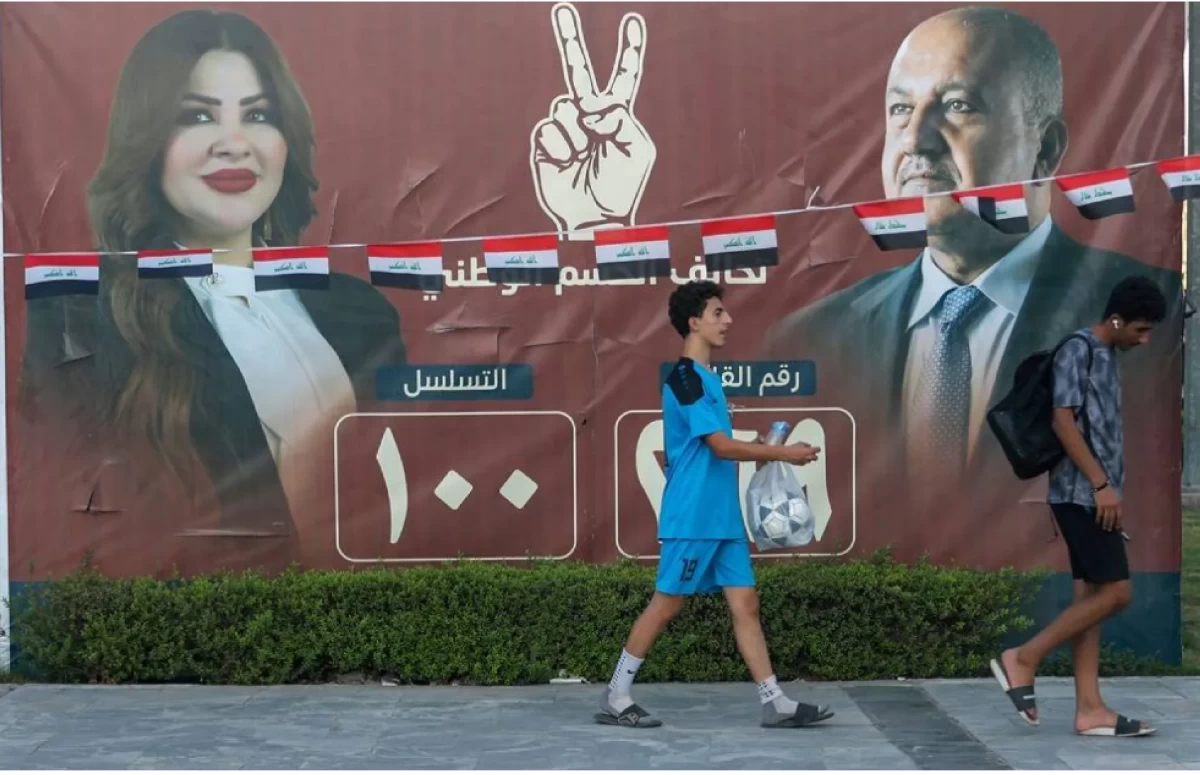 People walk past electoral billboards on a street in Baghdad on October 14, 2025, ahead of parliamentary elections on November 11 (AFP photo)