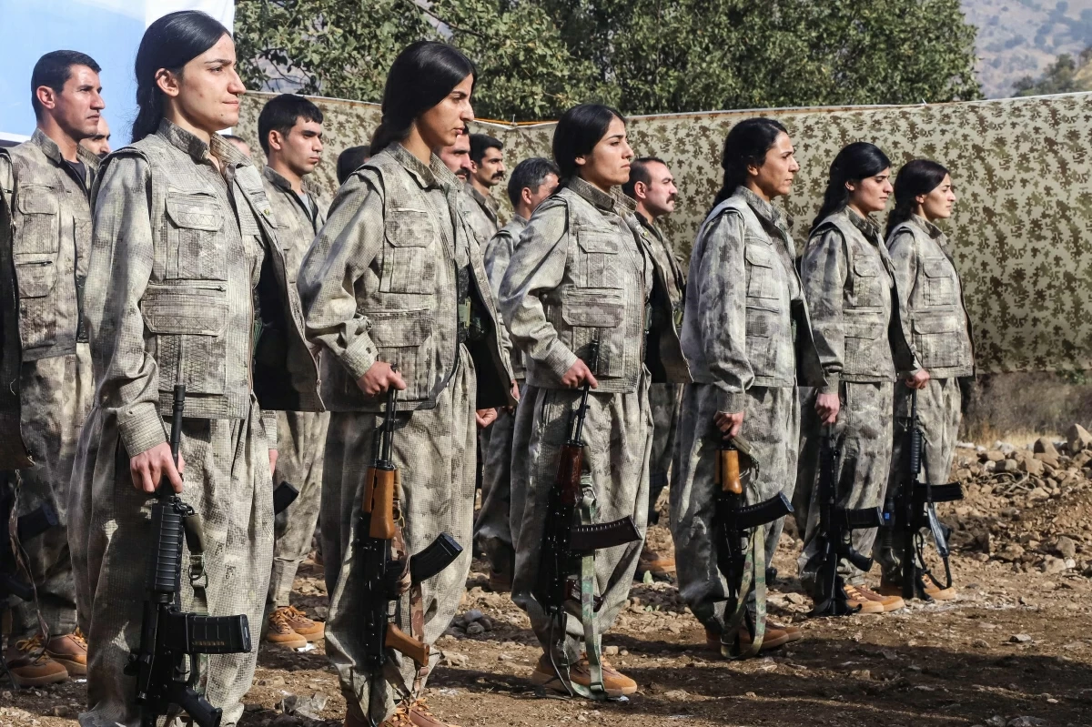 Kurdistan Workers' Party fighters, who reportedly withdrew from Turkey with their weapons, stand at attention during a ceremony in the Qandil area of northern Iraq on October 26, 2025 (AFP photo)