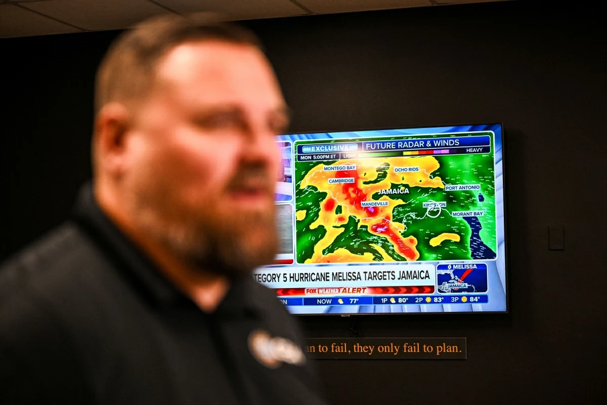 A weather news channel displays Hurricane Melissa updates as Billy Richardson, Director of US warehousing of Global Empowerment Mission, speaks during an interview with AFP at Global Empowerment Mission Headquarters in Miami, Florida, on October 27, 2024 (AFP photo)