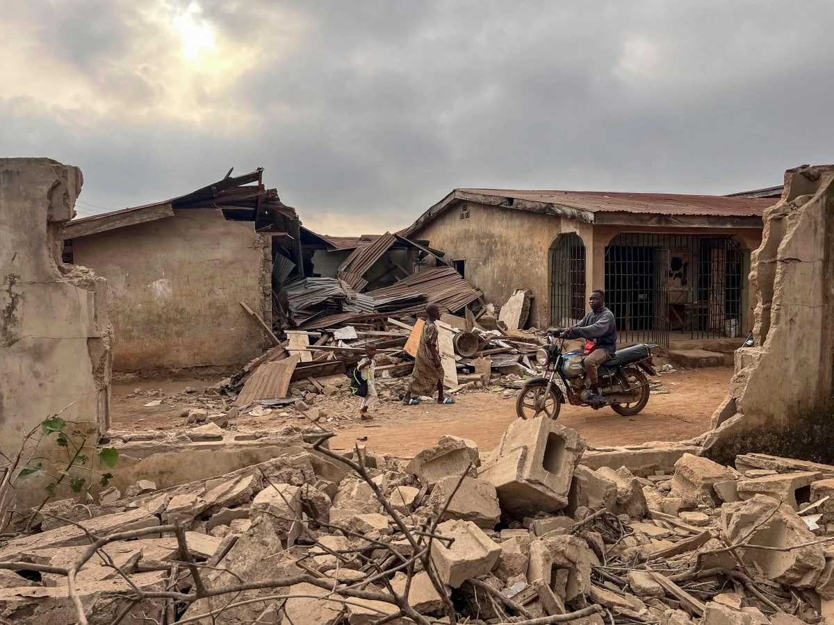 Residents and a motorcyclist move between destroyed structures in Offa on December 27, 2025 caused by debris from expended munitions that fell from US strikes on unspecified militants linked to extremists in Nigeria (AFP photo)