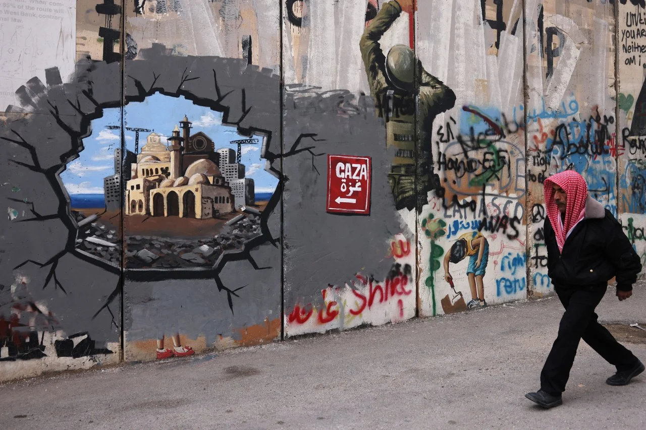 A man walks past graffiti representing the reconstruction of Gaza on the separation barrier in Bethlehem, the occupied West Bank (AFP photo)