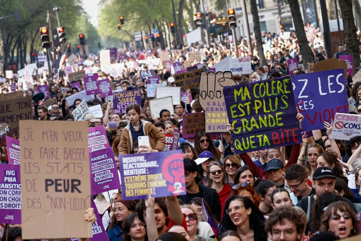Protestors hold signs during a march marking the International Women's Day in Paris on March 8, 2026 (AFP photo)