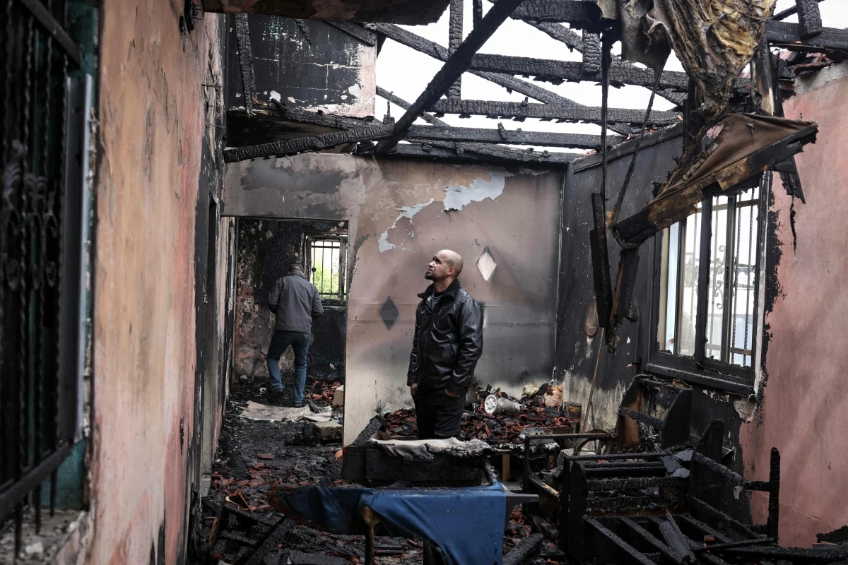 A Palestinian man inspects the remains of his burnt-out family home following a reported attack by Israeli settlers in the village of Fandaqumiya, southwest of Jenin, in the Israeli-occupied West Bank on March 22, 2026 (AFP photo) 