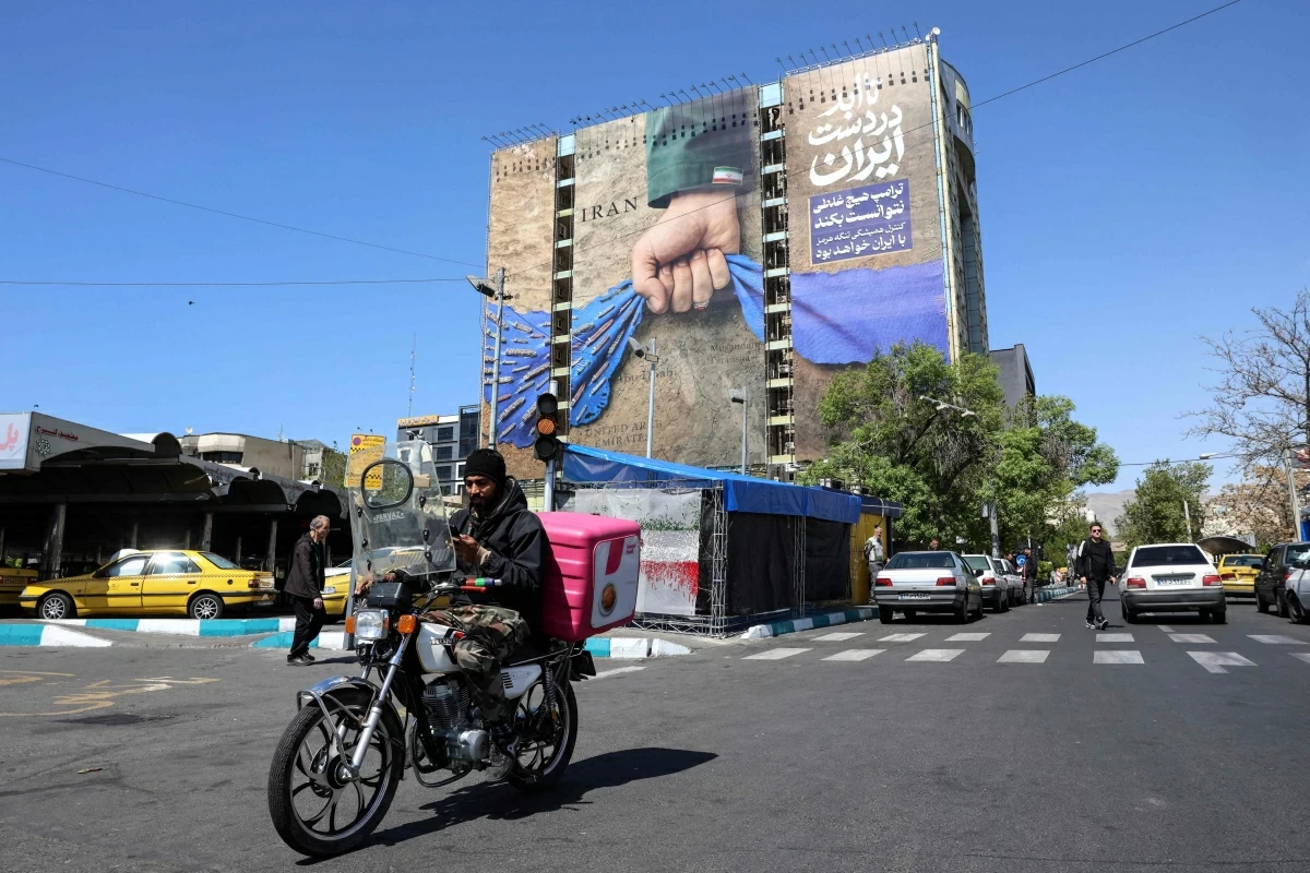 A man rides past a large billboard referring to the Strait of Hormuz in Tehran's Vanak Square on April 15, 2026
(AFP photo)