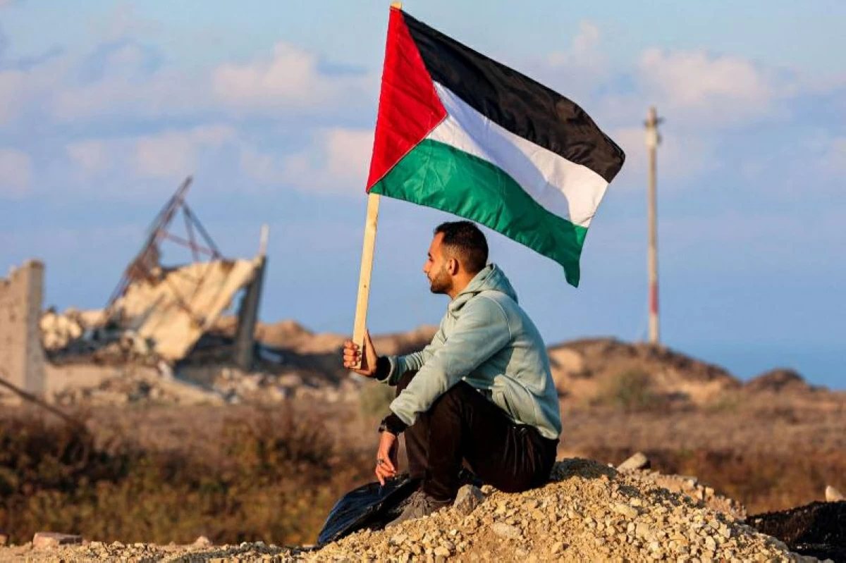 A man holds a Palestinian flag as he watches displaced Gazans crossing the Netzarim corridor from the southern Gaza Strip into Gaza City, January 27, 2025
(AFP photo)