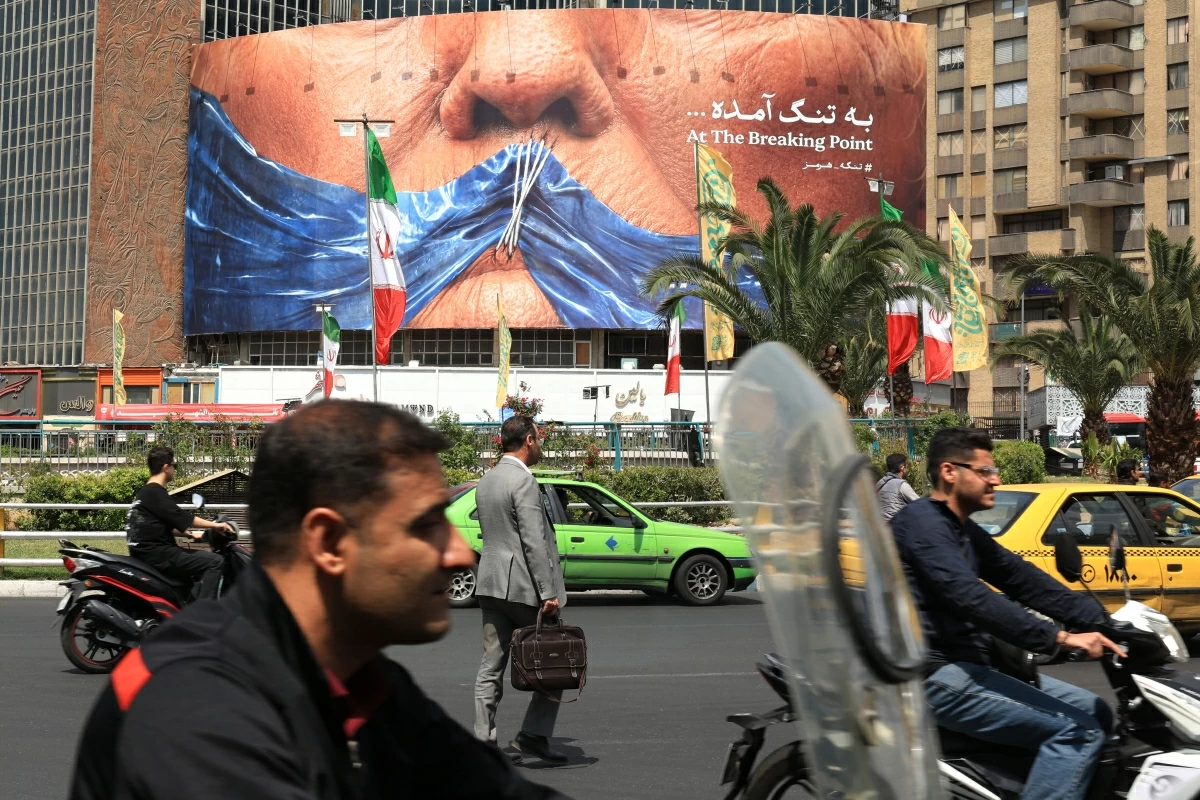 Commuters make their way past an anti-US billboard referring to President Donald Trump and the Strait of Hormuz, installed on a building at the Valiasr Square in Tehran on May 2, 2026 (AFP photo)