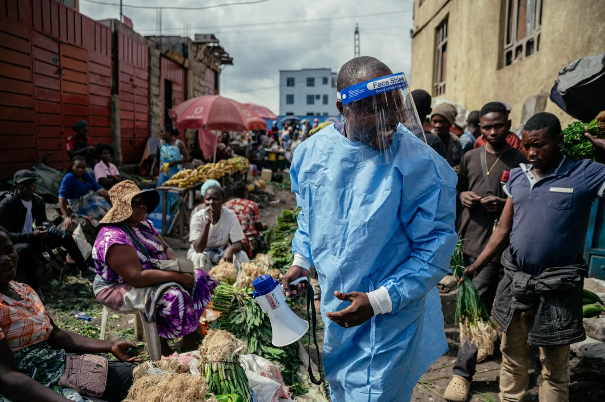 Cousin Kasumbo, president of the U Report Goma community, dressed in protective equipment, raises awareness among traders alongside young members of the U Report Goma group who continue awareness activities at Alanine market using megaphones and focus group discussions as part of Ebola prevention and awareness measures in Goma, on May 29, 2026 (AFP photo)