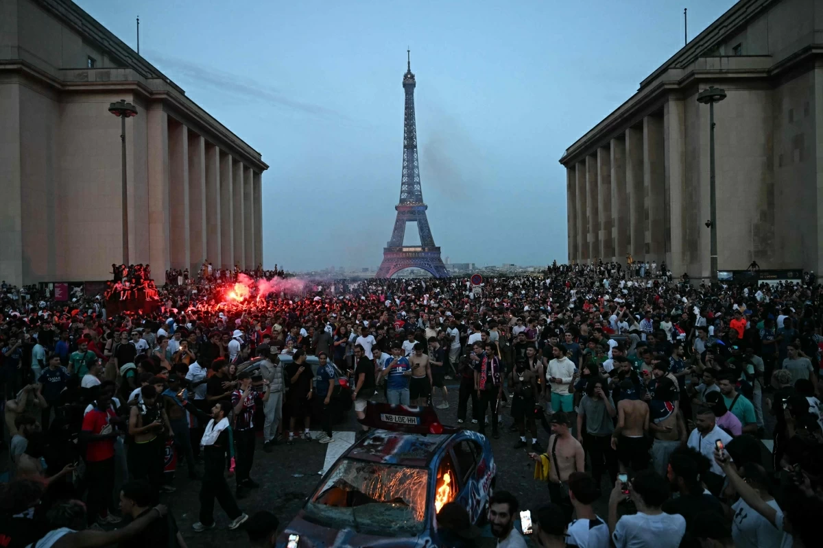 PSG supporters gather around a car that was set ablaze as they celebrate their team's win in the UEFA Champions League final between Paris Saint-Germain (PSG) and Arsenal FC played in Budapest, at Place du Trocadero opposite the Eiffel Tower in Paris on Saturday (AFP photo)