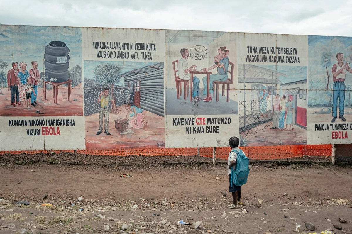 A child returning from school stops to look at Ebola awareness illustrations displayed on the signboards of the Ebola Treatment Center (ETC) in Munigi on June 2, 2026 (AFP photo)