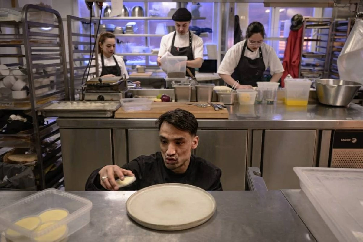 Chef Habi Khaliqdad removes dishes from a fridge as members of his brigade cook in the background, in Iulissat, Greendland (AFP photo)
