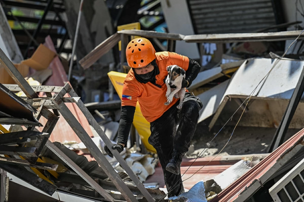 A responder carries a rescue dog while conducting search and rescue operations in a collapsed building after a 7.8 magnitude earthquake in General Santos City on June 9, 2026 (AFP photo)