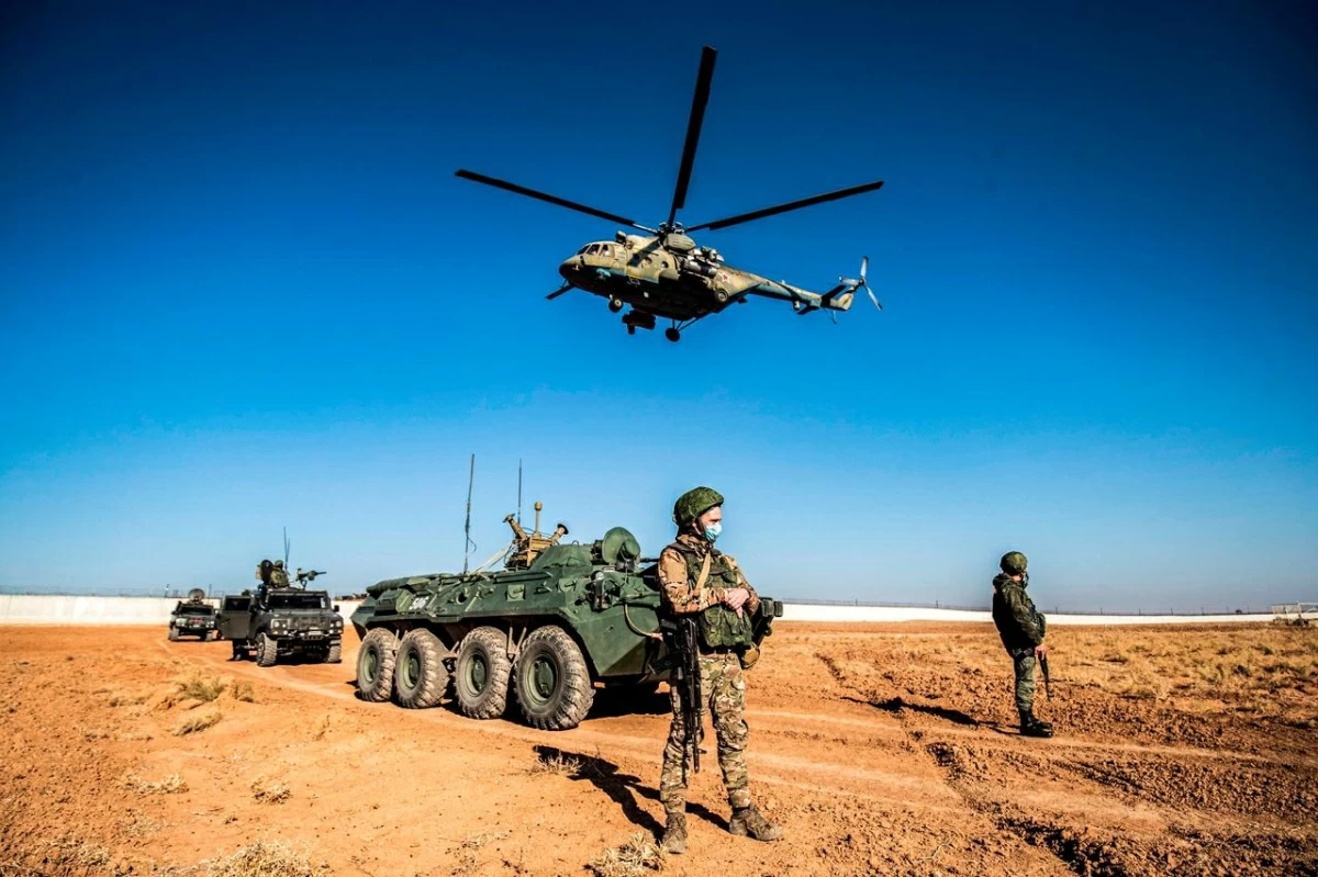 A Russian Mil Mi-17 military helicopter flies by soldiers and military vehicles during a joint Russian-Turkish patrol in the eastern countryside of the town of Darbasiyah near the border with Turkey in Syria's northeastern Hasakah province, December 7, 2020 (AFP photo)