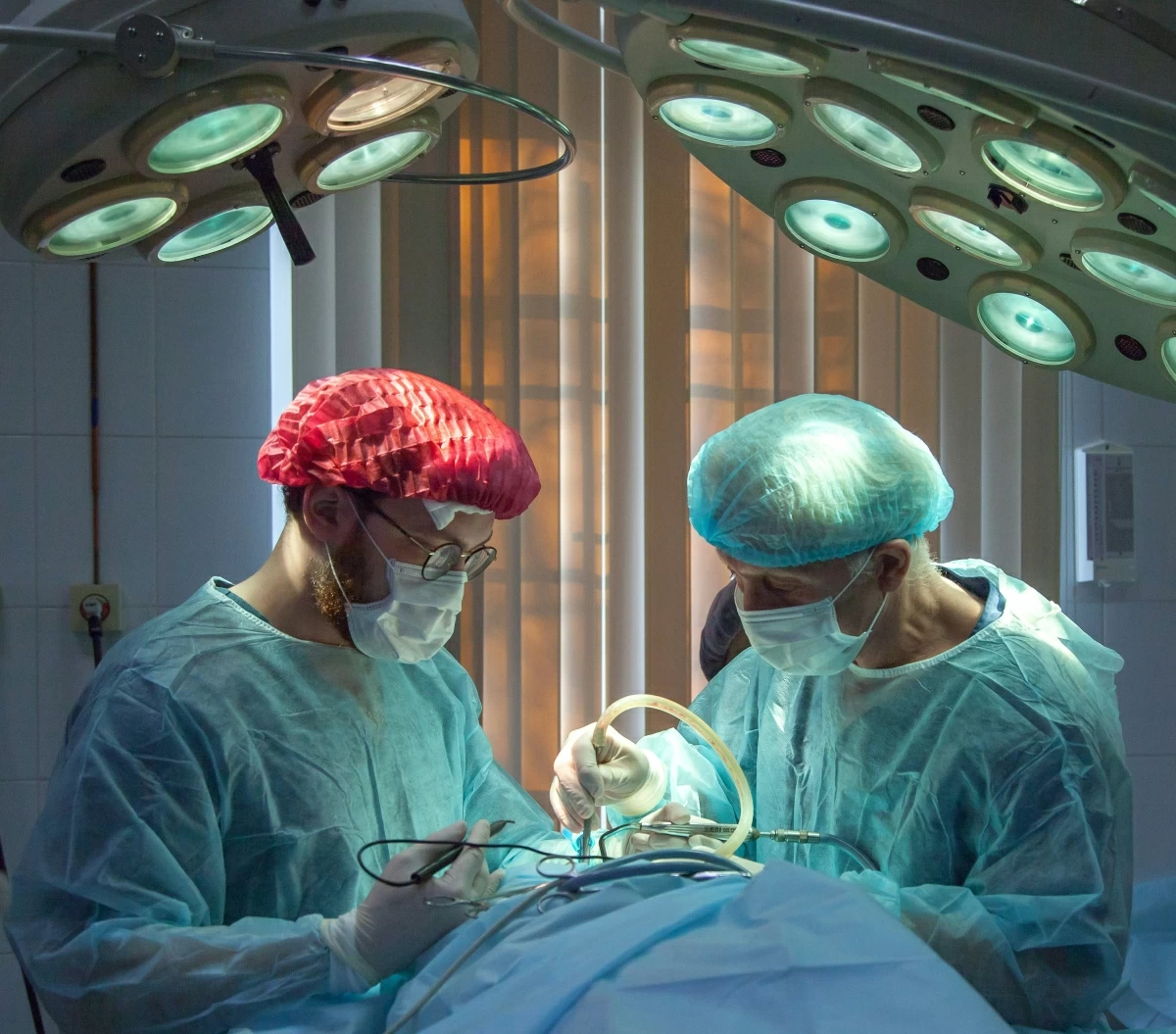 In this photo, surgeons are seen performing a surgical procedure under high-intensity operating lights (Photo courtesy of Unsplash)