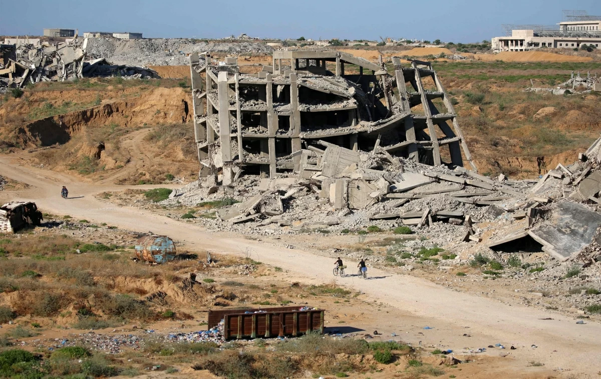 Men ride bicycles past a heavily-damaged building at the Nuseirat camp for Palestinian refugees in the central Gaza Strip on Friday (AFP photo)