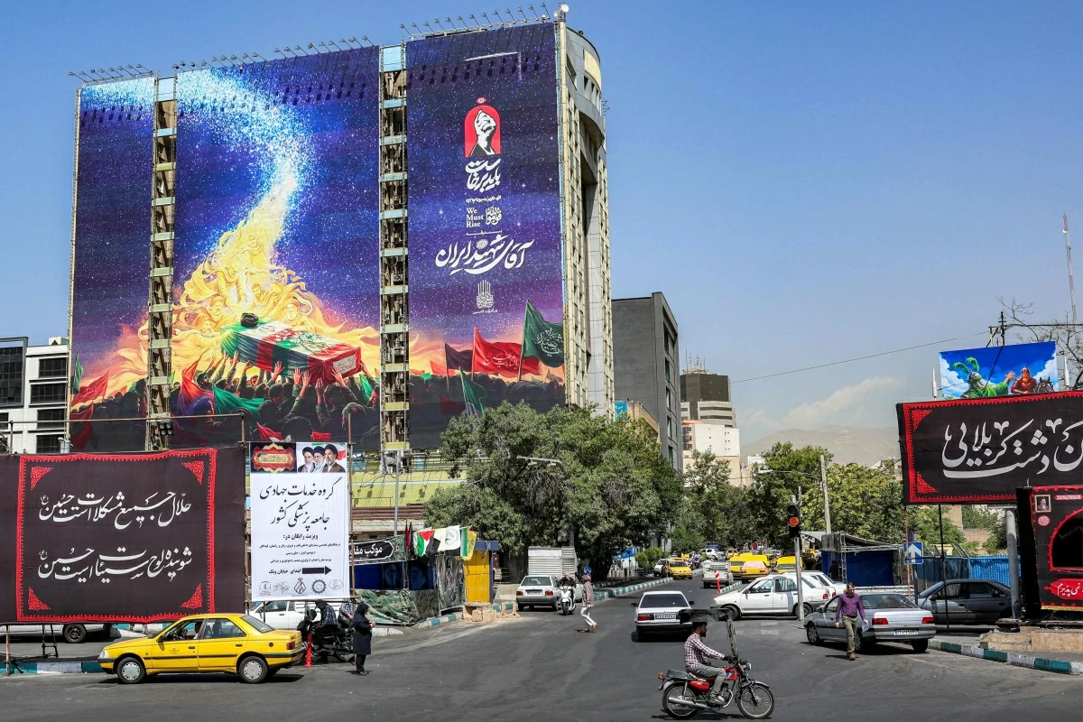 Motorists drive vehicles past a mural displayed on the facade of a building depicts late figures aligned with the Iranian government at Vanak Square in Tehran on June 29, 2026 (AFP photo)