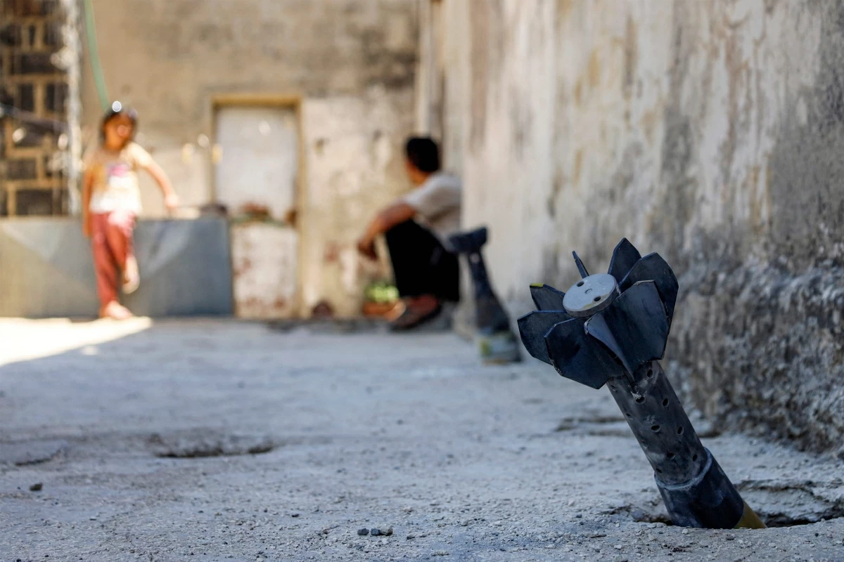 A man speaks with a child while sitting near an unexploded artillery shell that fell during reported overnight Israeli bombardment that hit the village of Abidin in Syria's southwestern Daraa province, close to the Golan Heights, on June 29, 2026 (AFP photo)