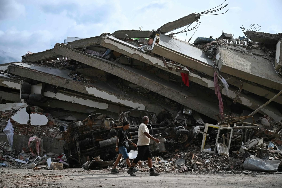 Men walk along the ruins of collapsed buildings in Caraballeda, La Guaira state, Venezuela, on July 8, 2026, following powerful earthquakes that struck the region (AFP photo) 
