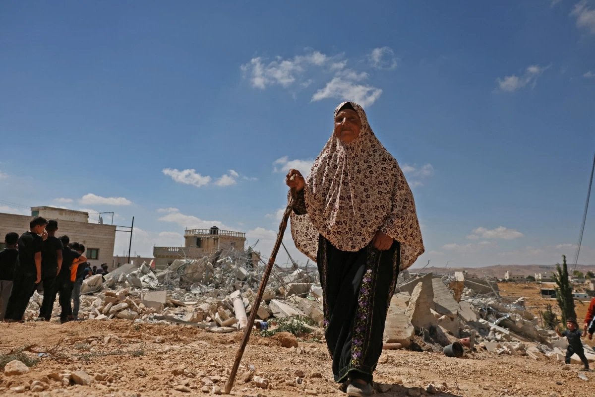A woman walks past the rubble of a Palestinian home demolished by Israeli forces in the village of al-Rifayia, south of Hebron in the occupied West Bank, on July 9, 2026 (AFP photo)