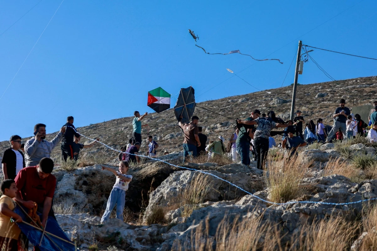 Palestinians and solidartiy activists fly kites towards the Israeli settelment of Har Bracha from the village of Burin, south of Nablus in the occupied West Bank on July 10, 2026 (Photo by Jaafar ASHTIYEH / AFP)
