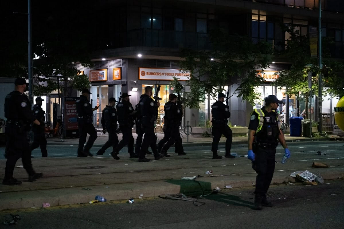 Police officers and other law enforcement personnel are seen at the intersection of St. Clair West and Arlington Avenue, near the site of a shooting that occurred at the Salsa on St. Clair Festival in Toronto on the evening of July 11, 2026 (AFP video)