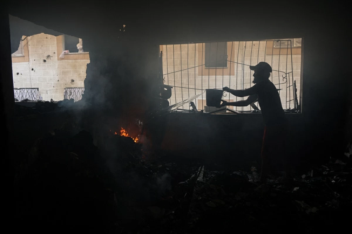 A Palestinian man sprays water in an attempt to extinguish a fire in a house after an Israeli airstrike in Gaza City on July 21, 2026 (AFP photo)