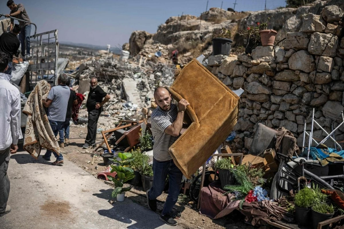 A Palestinian man carries a chair as he helps move salvaged belongings of familes whose house was demolished by Israeli security forces in the village of Nahalin, southwest of Bethlehem in the Israeli occupied West Bank on July 22, 2026
(AFP photo)