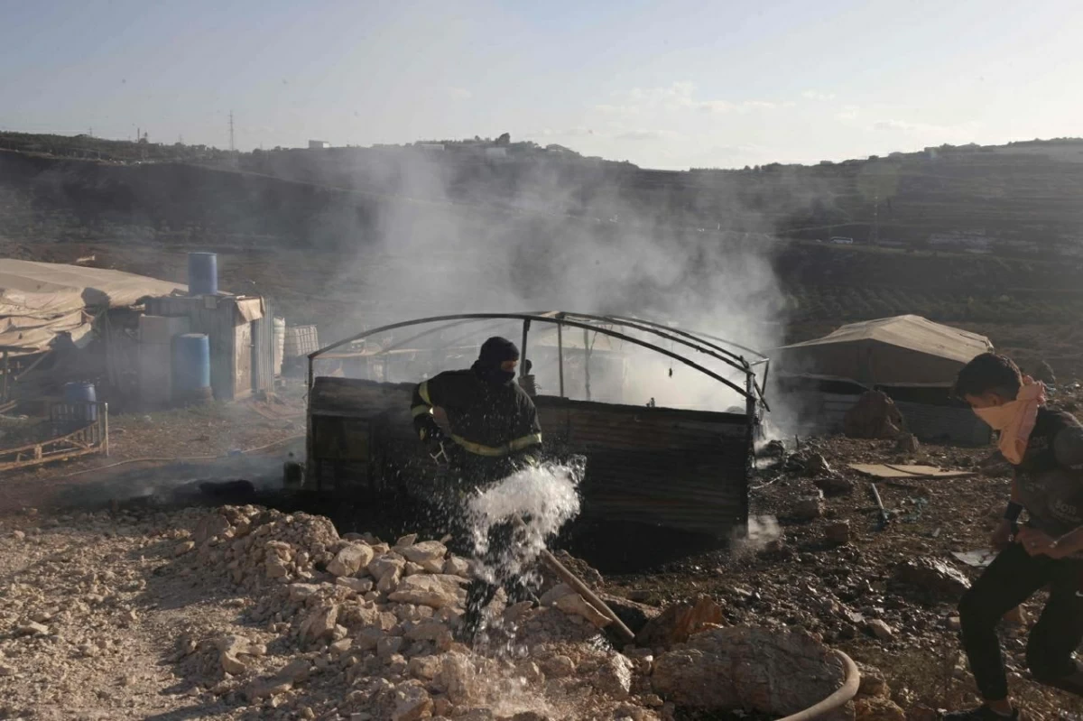 A Palestinian firefighter and a resident douses a fire after a tent was torched in an attack reportedly by Israeli settlers in the Palestinian village of Sarra, west of the the city of Nablus in the Israeli-occupied West Bank (AFP photo)