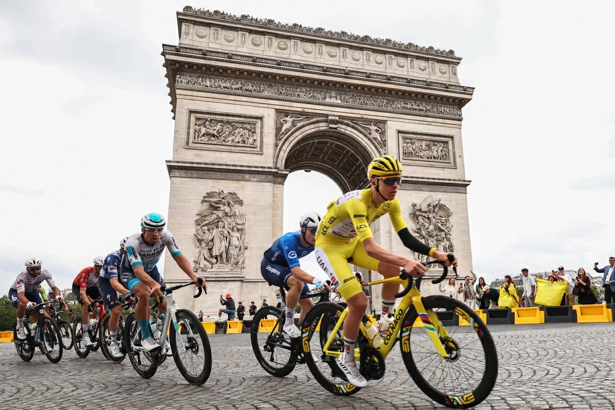 This photograph taken on July 27, 2025, shows UAE Team Emirates - XRG team's Slovenian rider Tadej Pogacar wearing the overall leader's yellow jersey cycling with the pack of riders (peloton) past the Arc de Triomphe on Place Charles de Gaulle (ATFP photo)