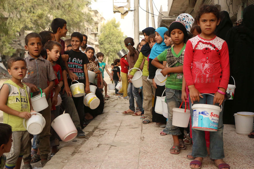 Syrian children, who were displaced with their families from their houses due to the ongoing conflict in Syria, queue up to receive food aid in the rebel side of the northern city of Aleppo, on Monday (AFP photo)
