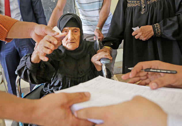 Amnah Sayed Mossa, 80, is given assistance by election officials as she prepares to cast her vote at a polling station during the first round of parliamentary elections in Giza, Cairo, Egypt, Sunday (AP photo)