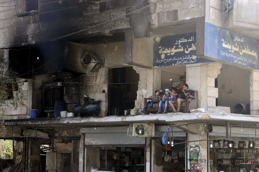 Residents sit on a couch on a balcony of a damaged building in Aleppo’s Al Shaar neighbourhood, Syria, on Saturday (Reuters photo by Abdalrhman Ismail)