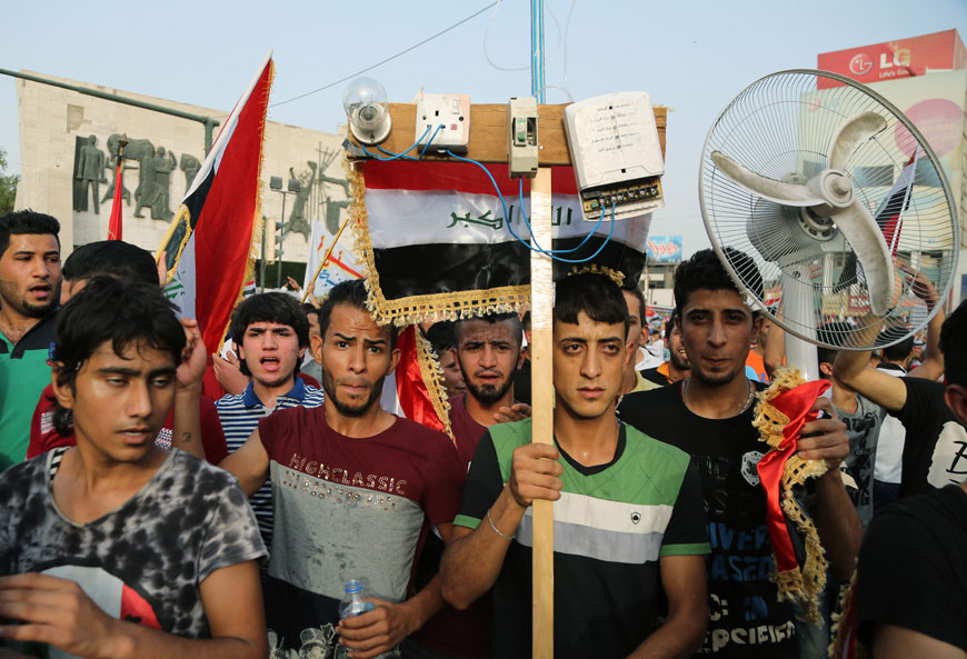 In this August 7 file photo, protesters chant anti-Iraqi government slogans as they carry national flags and a fan in Tahrir Square in Baghdad, Iraq, Friday (AP photo)