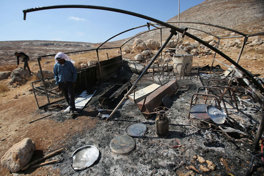 A Palestinian bedouin checks a torched tent in Ein Samiya, a village in the Israeli-occupied  West Bank, on Thursday after a reported attack by Jewish extremists during which they also sprayed graffiti in Hebrew reading, ‘administrative revenge’ (AFP photo)