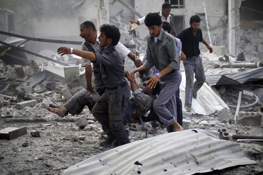 Syrian emergency personnel carry a wounded man following air strikes by Syrian government forces on a marketplace in the rebel-held area of Douma, east of the capital Damascus, on Sunday (AFP photo)