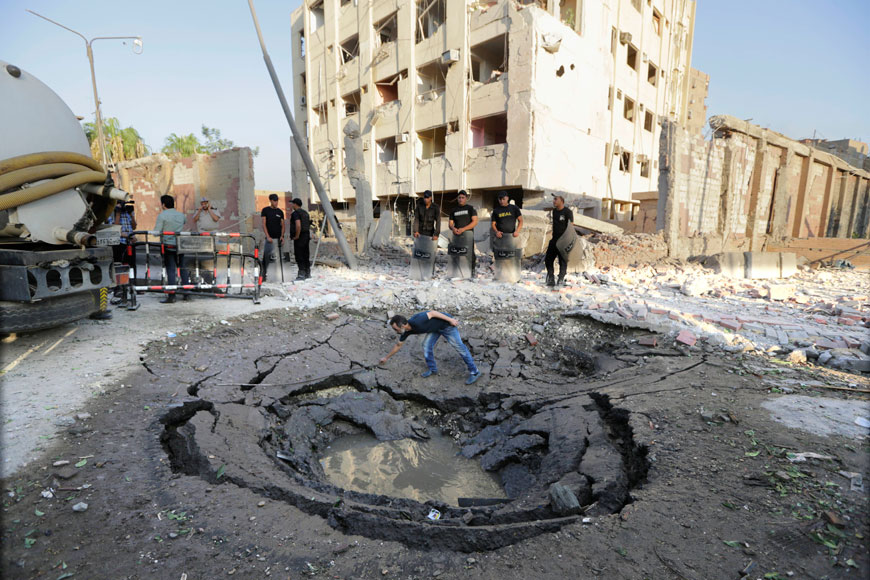 An Egyptian worker checks a hole believed to be caused by the bombing in the street outside the national security building early Thursday (AP photo)