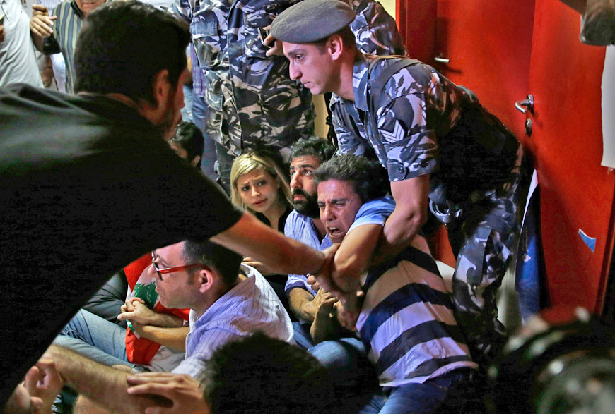 A Lebanese policeman (right) tries to drag away an anti-government activist during a sit-in protest against Environment Minister Mohammad Machnouk, inside the environment ministry, in downtown Beirut, Lebanon, Tuesday (AP photo)