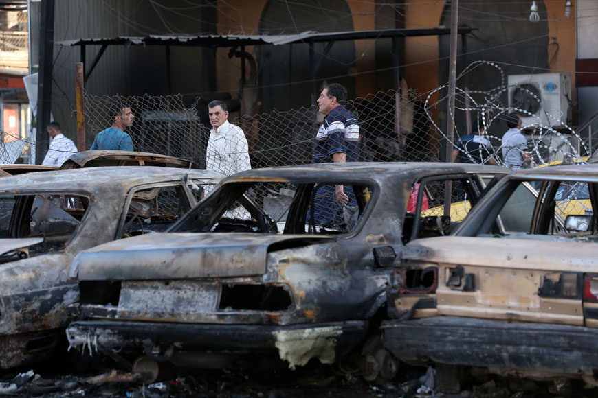 Civilians inspect the aftermath of a car bombing near a restaurant in a commercial area of central Baghdad, Iraq, Tuesday (AP photo)