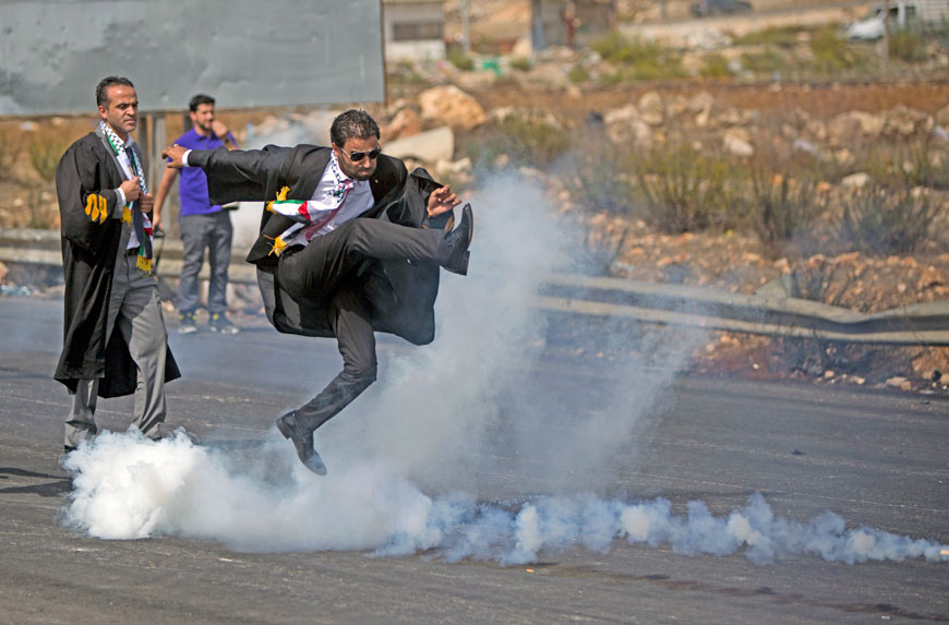 A lawyer kicks a tear gas canister back towards Israeli forces during a demonstration in Ramallah on Monday called for by the Palestinian Bar Association in solidarity with protesters at Al Aqsa Mosque compound (AP photo)