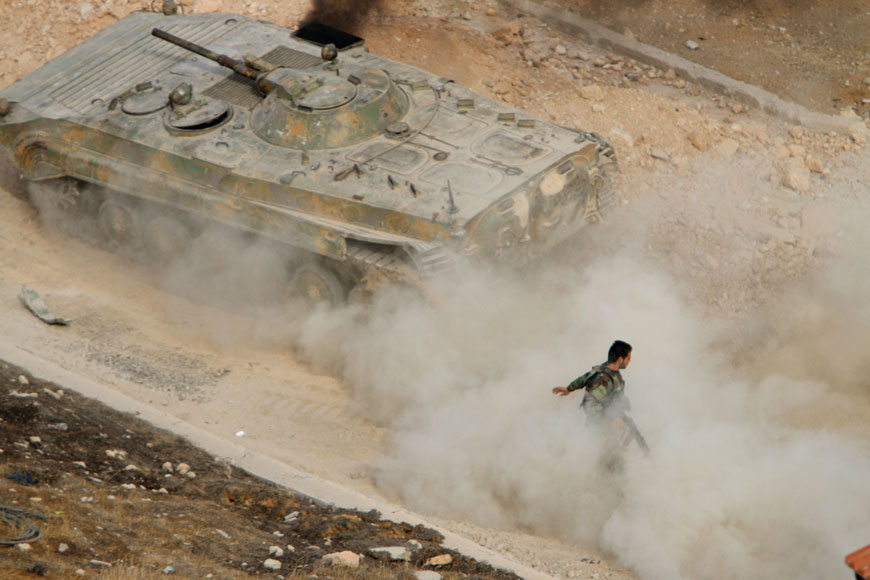 A Syrian armoured personnel carrier moves, raising dust in Harasta, northeast of Damascus, on Thursday (AP photo)