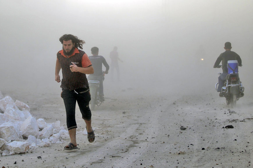 Residents run through dust at a site damaged by what activists said were air strikes carried out by the Russian air force in the rebel-controlled area of Maaret Al Numan town in Idlib province, Syria, on Saturday (Reuters photo)