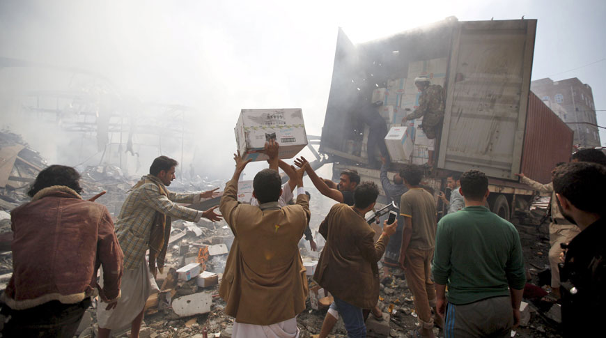 People move boxes of cake from a damaged truck outside a food storage warehouse hit by a Saudi-led air strike in Yemen’s capital Sanaa on Sunday (Reuters photo)