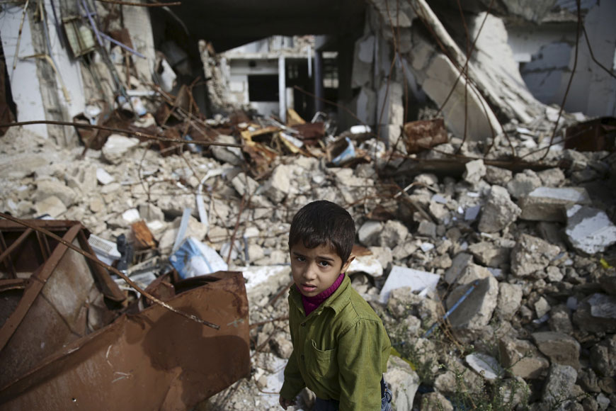 A boy walks amid damaged buildings in the town of Douma, eastern Ghouta in Damascus, Syria, on Monday (Reuters photo)