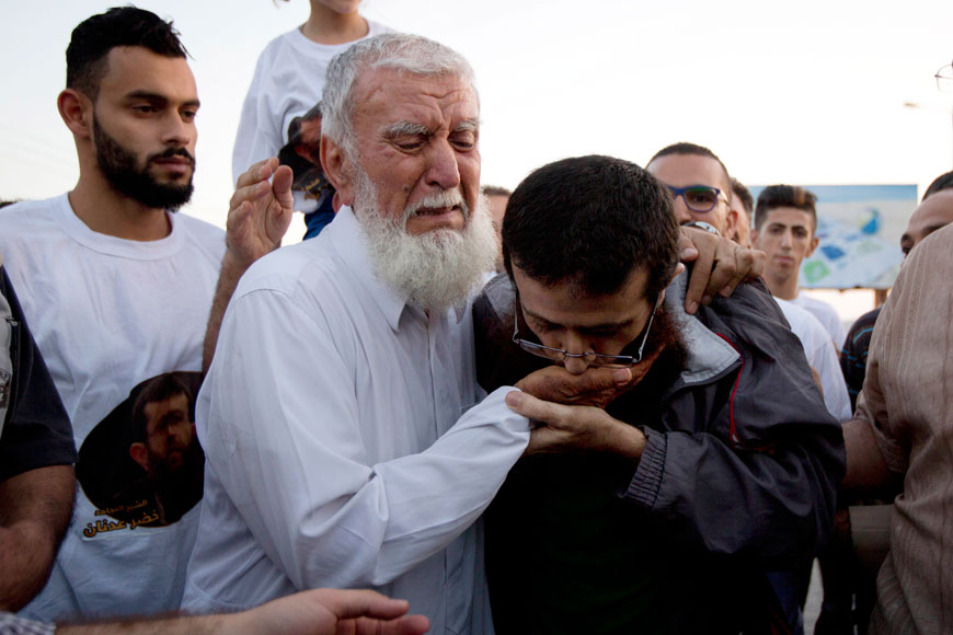 Palestinian Khader Adnan kisses his father’s hand after his release from an Israeli prison in the West Bank village of Arraba, near Jenin, Sunday (AP photo by Majdi Mohammed)