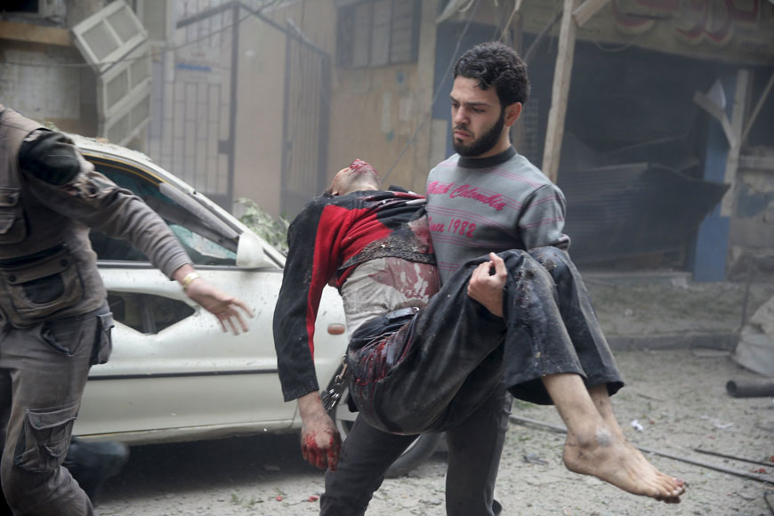 A resident carries an injured man through a site damaged from what activists said was an air strike by forces loyal to Syria’s President Bashar Assad in the town of Douma, Eastern Ghouta in Damascus, on Thursday (Reuters photo)