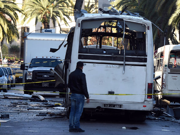A plain-clothed police officer walks beside the bus that exploded Tuesday in Tunis, on Wednesday  (AP photo)