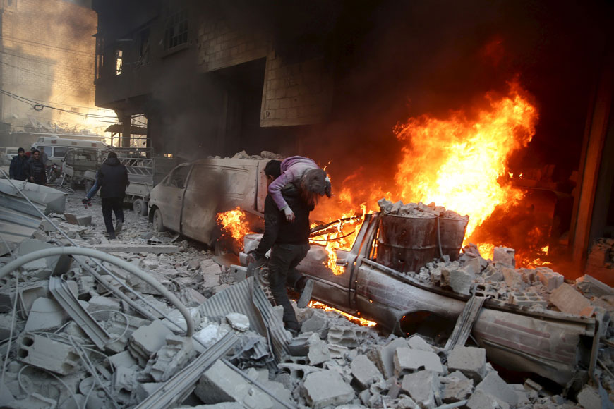  A man carries an injured child amidst rubble near a burning vehicle in a site damaged from what activists said was shelling by forces loyal to Syria’s President Bashar Assad in the town of Douma, eastern Ghouta in Damascus, Syria on Wednesday (Reuters photo by Bassam Khabieh)
